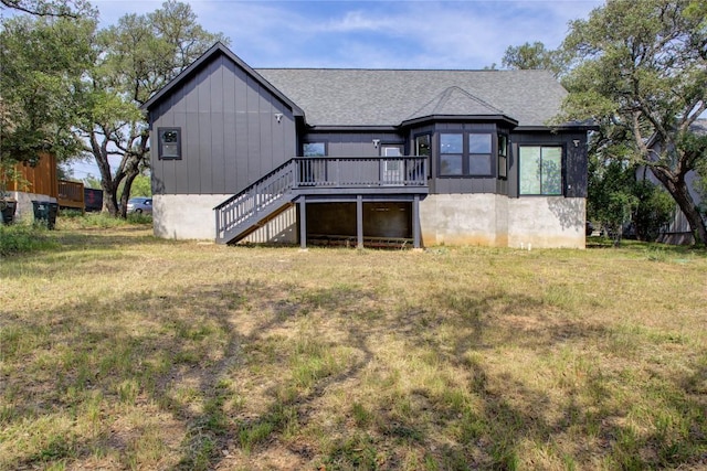 back of house featuring a wooden deck, a shingled roof, and a yard