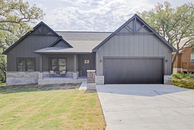 view of front of property with a garage, a shingled roof, a front lawn, driveway, and stone siding