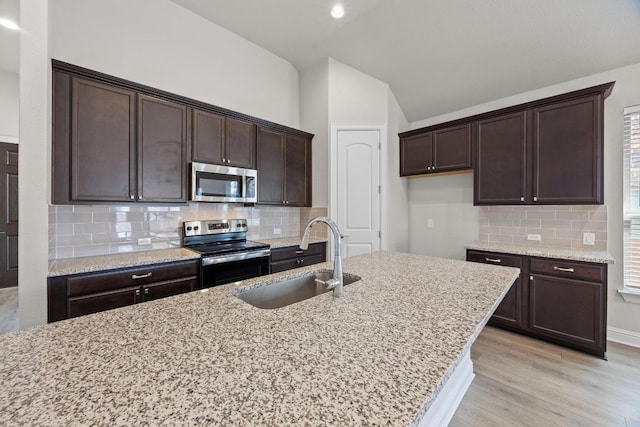 316 Barrel Bnd, Georgetown, TX 78628 - kitchen with appliances with stainless steel finishes, a sink, lofted ceiling, light wood-type flooring, and light stone counters