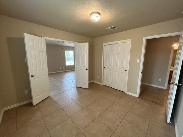 670 Covent Dr, Kyle, TX 78640 - unfurnished bedroom with light tile patterned flooring, a textured ceiling, baseboards, and a closet