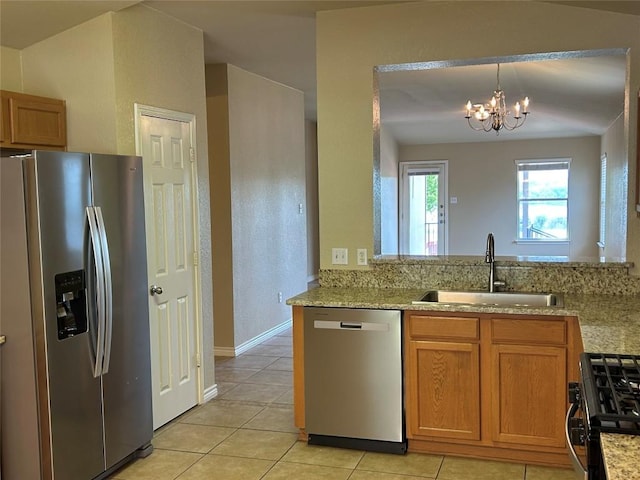 670 Covent Dr, Kyle, TX 78640 - kitchen with appliances with stainless steel finishes, a sink, light tile patterned floors, brown cabinets, and a chandelier