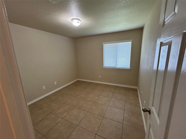 670 Covent Dr, Kyle, TX 78640 - empty room featuring a textured ceiling, light tile patterned flooring, and baseboards