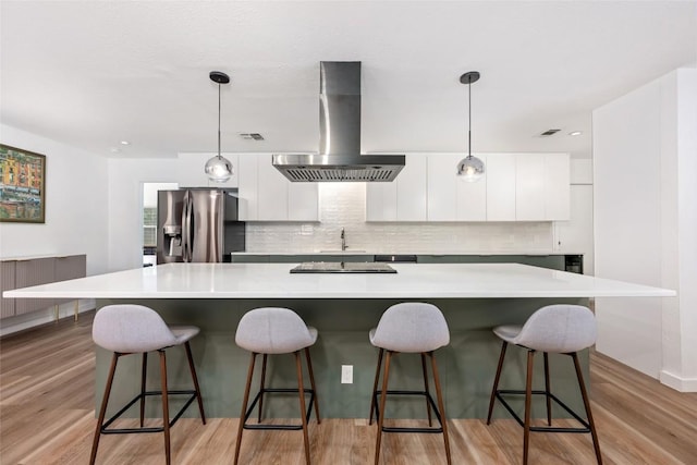 6309 Middleham Pl, Austin, TX 78745 - kitchen featuring stainless steel fridge, wall chimney range hood, modern cabinets, and white cabinets