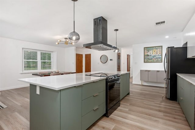 6309 Middleham Pl, Austin, TX 78745 - kitchen with black electric range, island exhaust hood, green cabinetry, a chandelier, and freestanding refrigerator