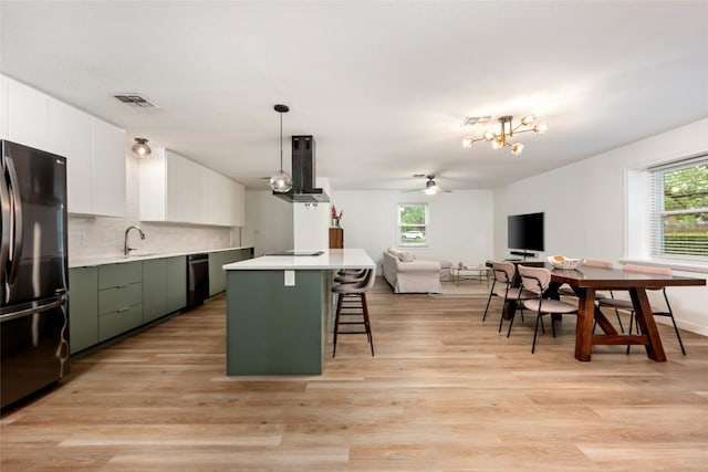 6309 Middleham Pl, Austin, TX 78745 - kitchen featuring black appliances, extractor fan, green cabinets, a breakfast bar, and healthy amount of natural light