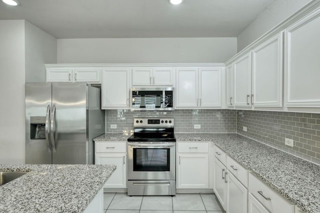3209 Ortman Dr, Pflugerville, TX 78660 - kitchen featuring appliances with stainless steel finishes, white cabinetry, tasteful backsplash, light tile patterned flooring, and light stone counters