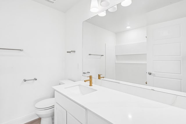 bathroom featuring toilet, vanity, wood finished floors, and baseboards
