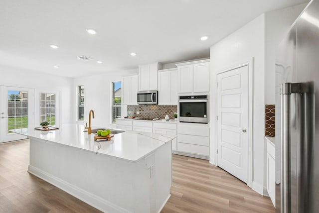 kitchen with appliances with stainless steel finishes, a sink, a center island with sink, plenty of natural light, and recessed lighting