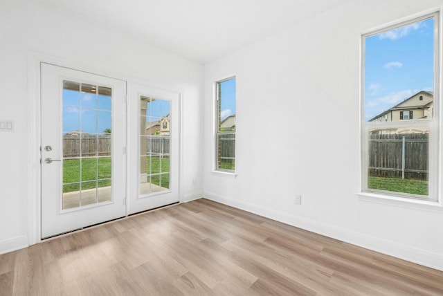 unfurnished room with light wood-style floors, baseboards, and healthy amount of natural light