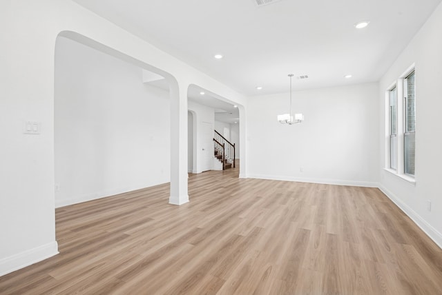 108 Redcliff Path, Kyle, TX 78640 - unfurnished living room with light wood finished floors, a chandelier, arched walkways, recessed lighting, and stairs