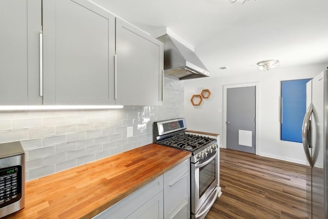 6209 Peggy St, Austin, TX 78723 - kitchen featuring appliances with stainless steel finishes, wood counters, wall chimney exhaust hood, decorative backsplash, and dark wood-style floors