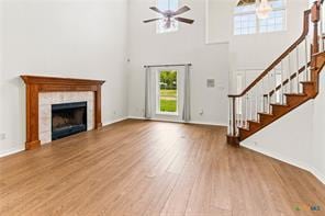 5012 Wildflower Ln, Temple, TX 76502 - unfurnished living room with plenty of natural light, wood finished floors, a ceiling fan, a towering ceiling, and stairs