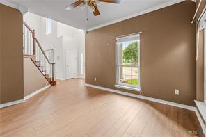 5012 Wildflower Ln, Temple, TX 76502 - unfurnished living room featuring ceiling fan, stairway, wood finished floors, and crown molding