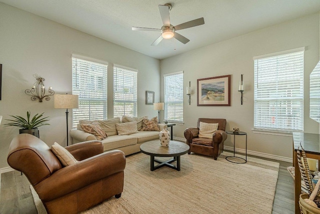 living area featuring a ceiling fan, baseboards, and light wood-style flooring
