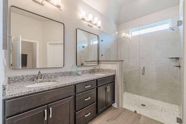 bathroom featuring a stall shower, double vanity, and wood finished floors