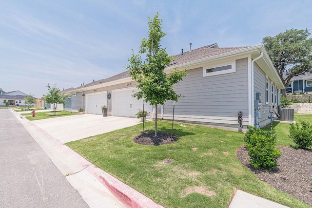 view of front of property featuring driveway, a garage, a front yard, and cooling unit