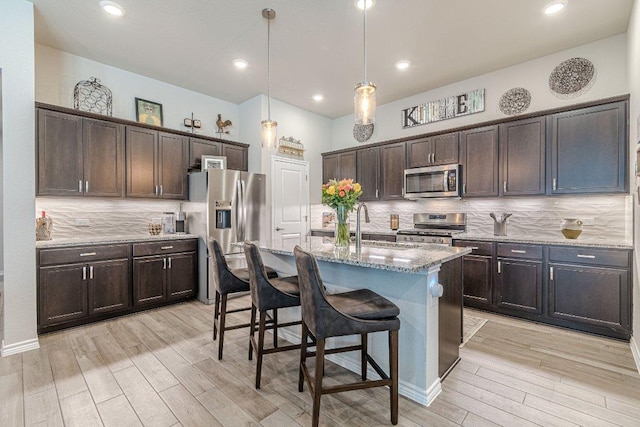 kitchen featuring appliances with stainless steel finishes, a sink, light wood-type flooring, tasteful backsplash, and recessed lighting