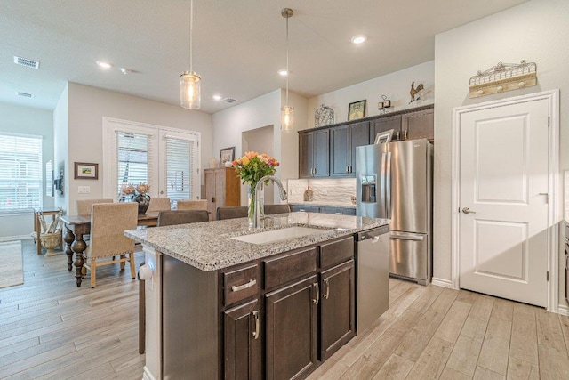 kitchen with a sink, stainless steel appliances, light wood-type flooring, dark brown cabinets, and recessed lighting