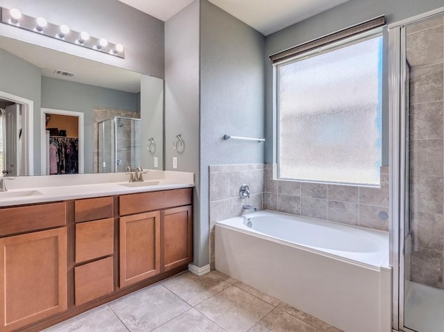 full bathroom featuring tile patterned flooring, a stall shower, a spacious closet, a garden tub, and double vanity