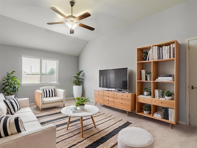 living area with a ceiling fan, light colored carpet, vaulted ceiling, and baseboards