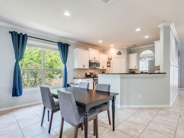 dining space featuring ornamental molding, healthy amount of natural light, light tile patterned flooring, recessed lighting, and arched walkways