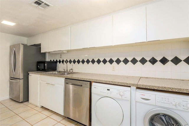 5601 Woodrow Ave Unit 109, Austin, TX 78756 - kitchen featuring appliances with stainless steel finishes, washing machine and clothes dryer, a sink, light tile patterned floors, and white cabinetry