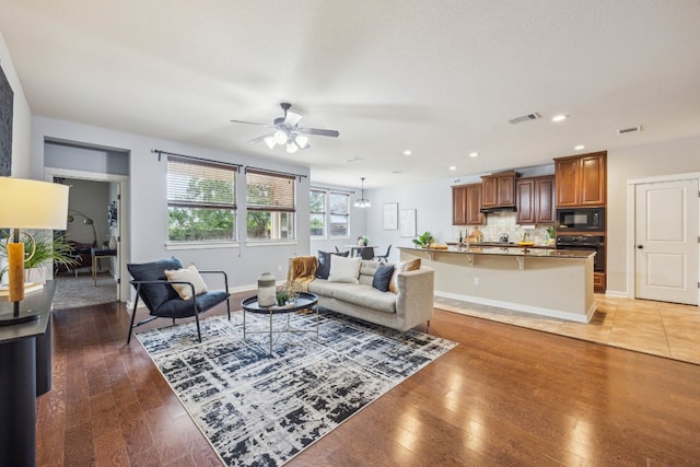 living room featuring a ceiling fan, light wood finished floors, recessed lighting, and baseboards