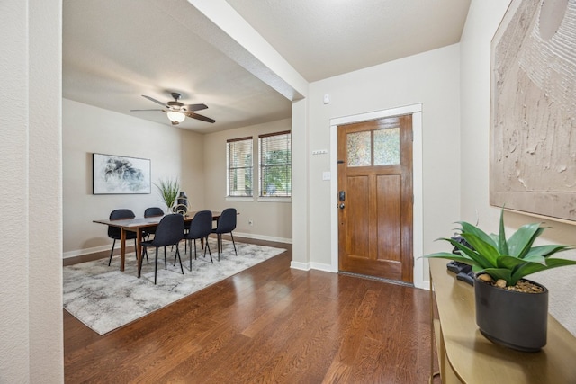 foyer entrance with dark wood finished floors, baseboards, and ceiling fan