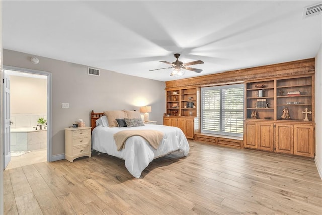 bedroom featuring light wood finished floors, ensuite bath, and a ceiling fan