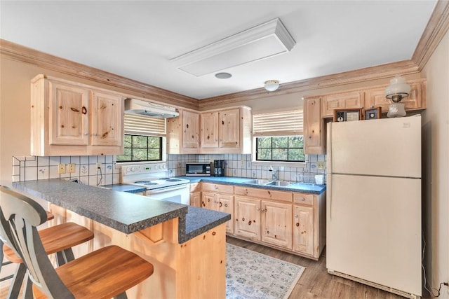 kitchen with white appliances, light brown cabinets, a sink, a peninsula, and crown molding