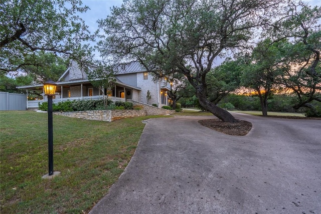 view of front facade featuring curved driveway, covered porch, and metal roof