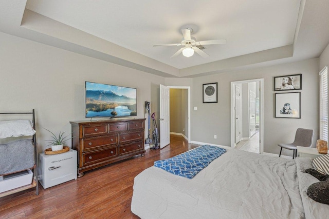 602 Leisurewoods Dr, Buda, TX 78610 - bedroom with a raised ceiling, wood finished floors, baseboards, ceiling fan, and ensuite bath