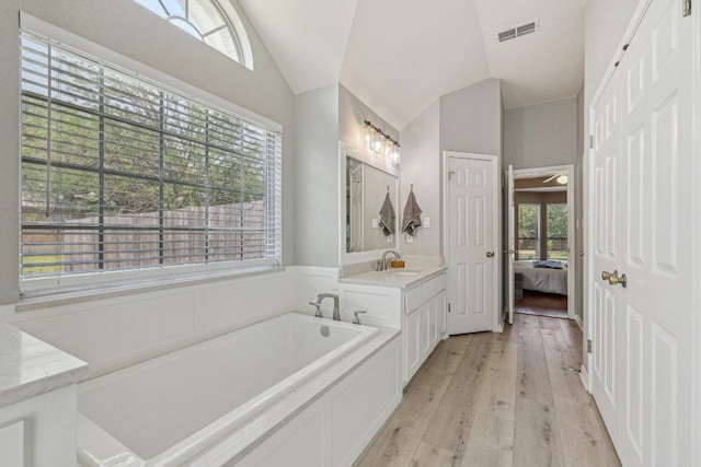 602 Leisurewoods Dr, Buda, TX 78610 - bathroom featuring vaulted ceiling, wood-type flooring, a garden tub, ensuite bathroom, and vanity