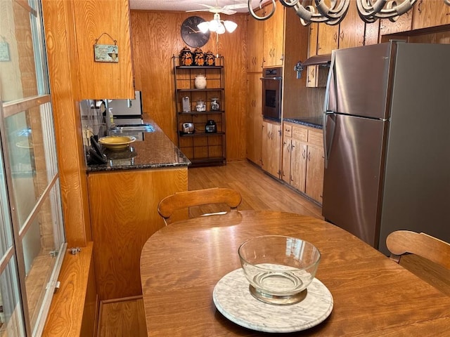 304 E Pheasant Rd, Highland Haven, TX 78654 - kitchen featuring appliances with stainless steel finishes, a sink, brown cabinetry, under cabinet range hood, and wood walls