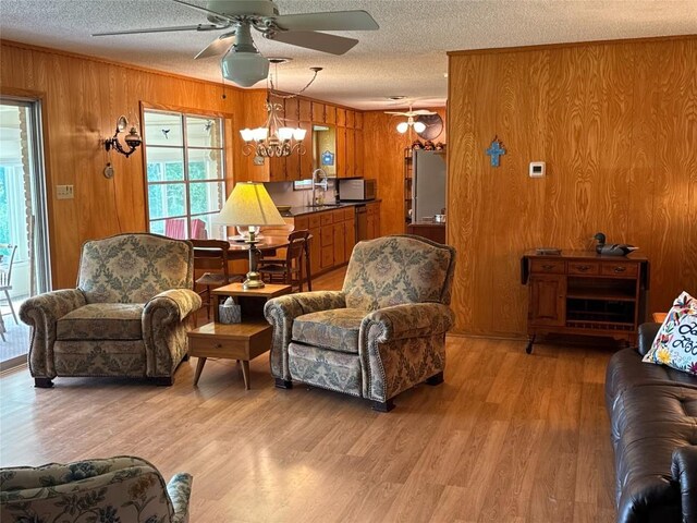 304 E Pheasant Rd, Highland Haven, TX 78654 - living area with a textured ceiling, ceiling fan, wood walls, a chandelier, and light wood-style floors