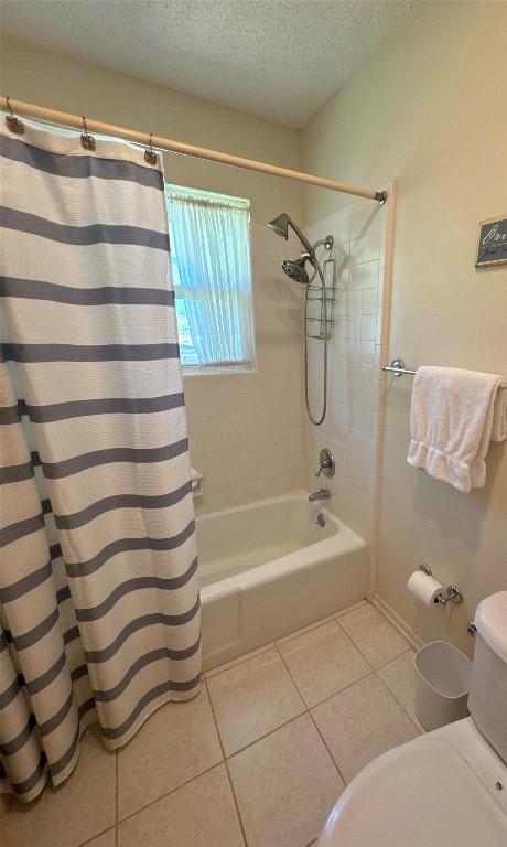 304 E Pheasant Rd, Highland Haven, TX 78654 - bathroom featuring a textured ceiling, tile patterned flooring, toilet, and shower / bath combo with shower curtain
