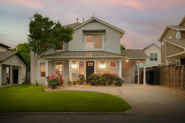 view of front facade featuring a standing seam roof, board and batten siding, metal roof, covered porch, and driveway