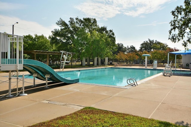 community pool with a water slide and a patio area