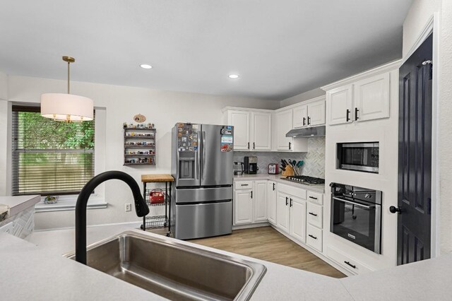 605 Galway Bay Cv, Pflugerville, TX 78660 - kitchen with appliances with stainless steel finishes, a sink, under cabinet range hood, white cabinets, and recessed lighting