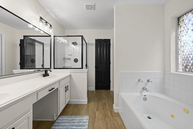 605 Galway Bay Cv, Pflugerville, TX 78660 - bathroom featuring double vanity, a tub with jets, wood finished floors, and a shower stall