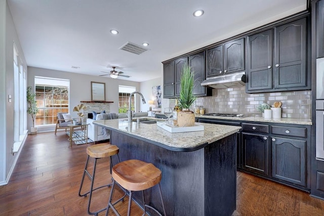 3831 Epperson Trl, Austin, TX 78732 - kitchen featuring a sink, a kitchen breakfast bar, a ceiling fan, dark wood-style flooring, and tasteful backsplash