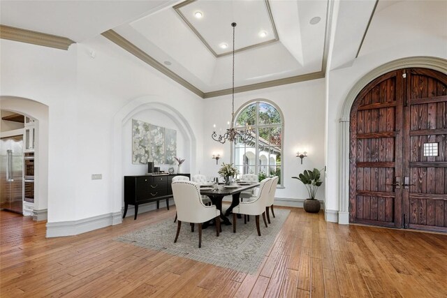16010 Canard Cir, Austin, TX 78734 - dining area with arched walkways, light wood-style floors, a tray ceiling, a chandelier, and ornamental molding