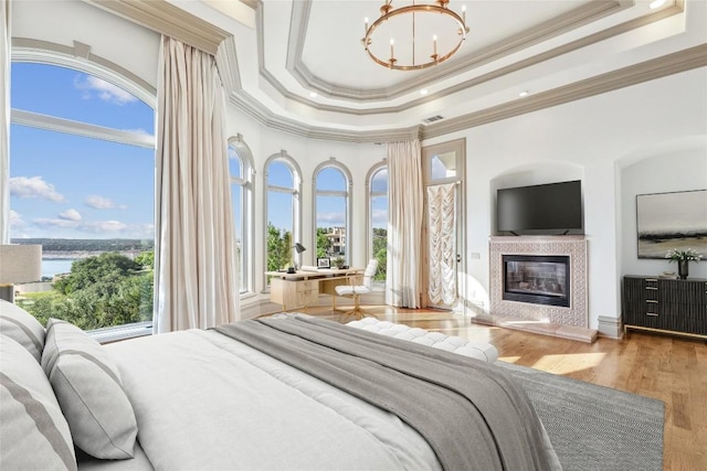 16010 Canard Cir, Austin, TX 78734 - bedroom featuring crown molding, a high end fireplace, a chandelier, a tray ceiling, and wood finished floors
