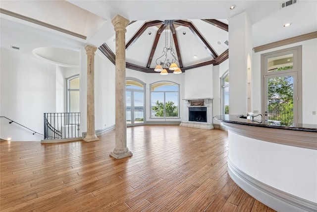 16010 Canard Cir, Austin, TX 78734 - unfurnished living room with healthy amount of natural light, decorative columns, a fireplace with raised hearth, a chandelier, and high vaulted ceiling
