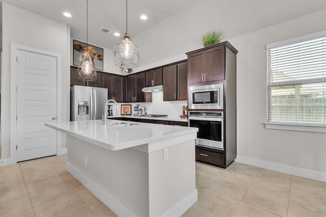 321 Millard St, Georgetown, TX 78628 - kitchen with stainless steel appliances, under cabinet range hood, dark brown cabinetry, light tile patterned floors, and light countertops