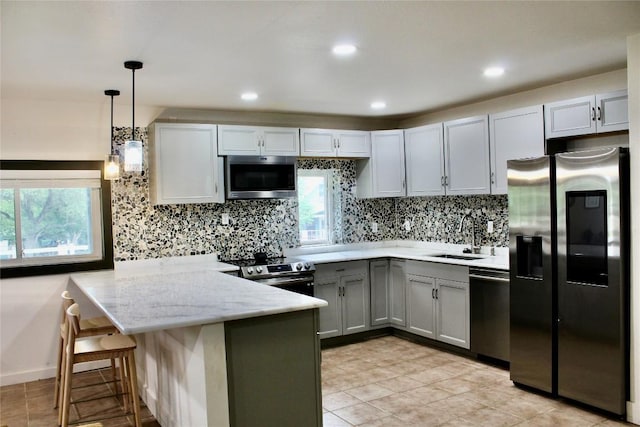 24701 Martin Ln, Spicewood, TX 78669 - kitchen featuring appliances with stainless steel finishes, a peninsula, decorative backsplash, gray cabinets, and decorative light fixtures