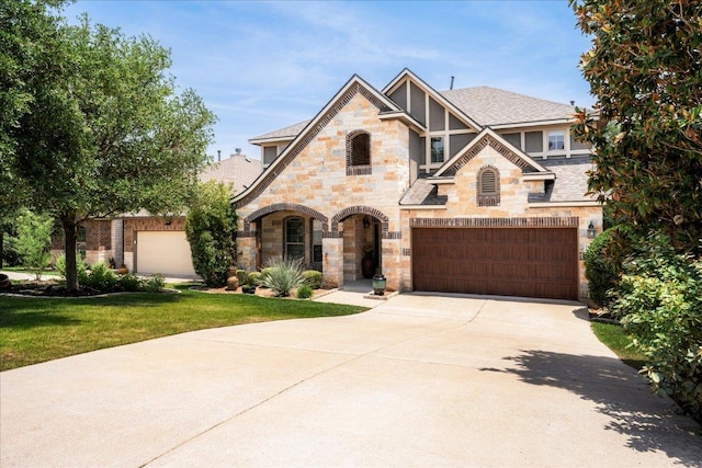 5517 Brady Bayou Cv, Austin, TX 78738 - tudor-style house featuring stone siding, a garage, driveway, and a front lawn