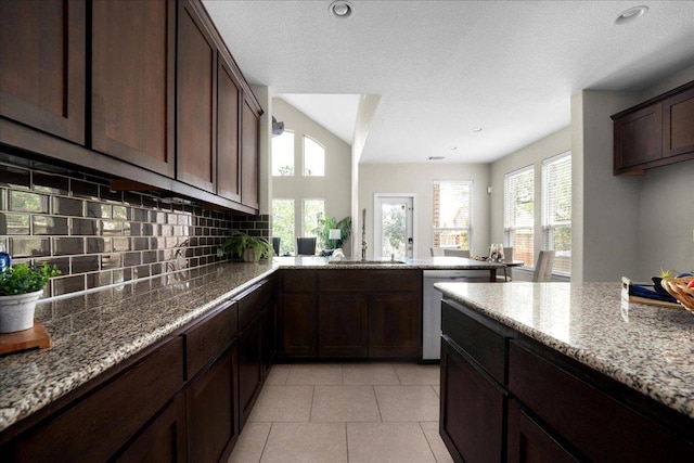 5517 Brady Bayou Cv, Austin, TX 78738 - kitchen with stainless steel dishwasher, light stone countertops, backsplash, dark brown cabinetry, and light tile patterned floors