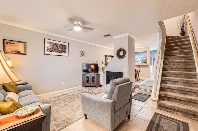 11901 Swearingen Dr Unit 30, Austin, TX 78758 - living room featuring stairs, ornamental molding, light tile patterned floors, ceiling fan, and a tile fireplace