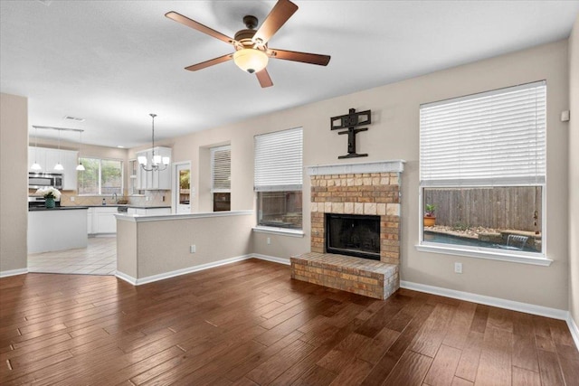 2502 Nightshade Dr, Cedar Park, TX 78613 - unfurnished living room featuring a chandelier, a ceiling fan, a sink, a brick fireplace, and baseboards